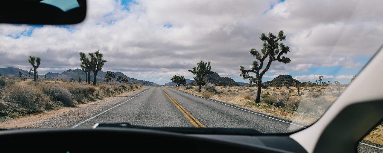 A picture of an open road on a cloudy day from inside a vehicle.